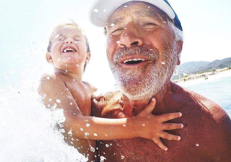 grandfather in surf with young boy