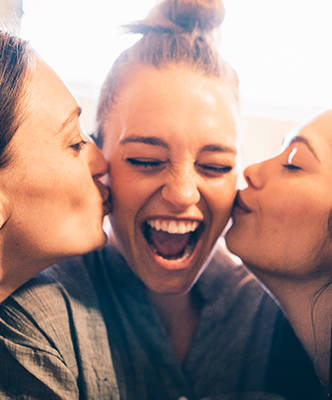 two girls kissing a smiling girl