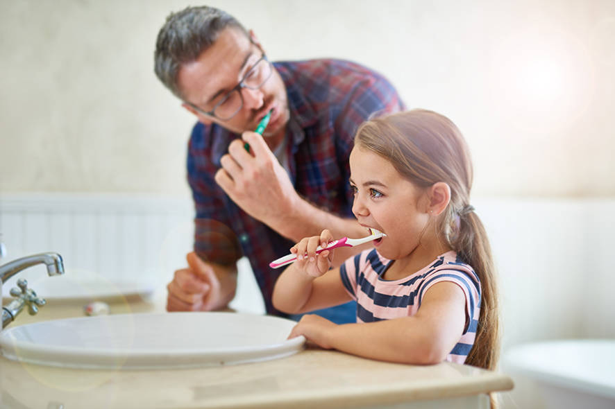 Father and daughter brushing their teeth