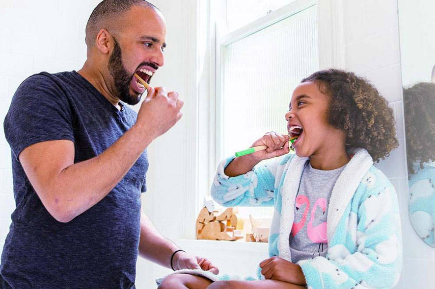 father  and daughter brushing teeth